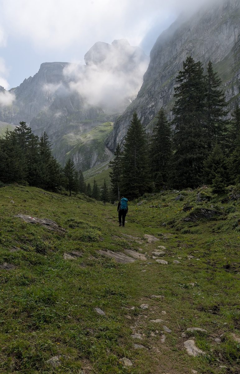 A hiker with a full pack on the Walenpfad trail in the Swiss Alps