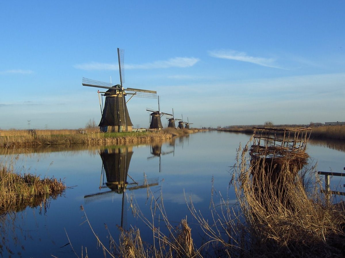 A row of UNESCO-listed windmills reflected in the water at Kinderdijk, a stop on Dutch waterway cruises