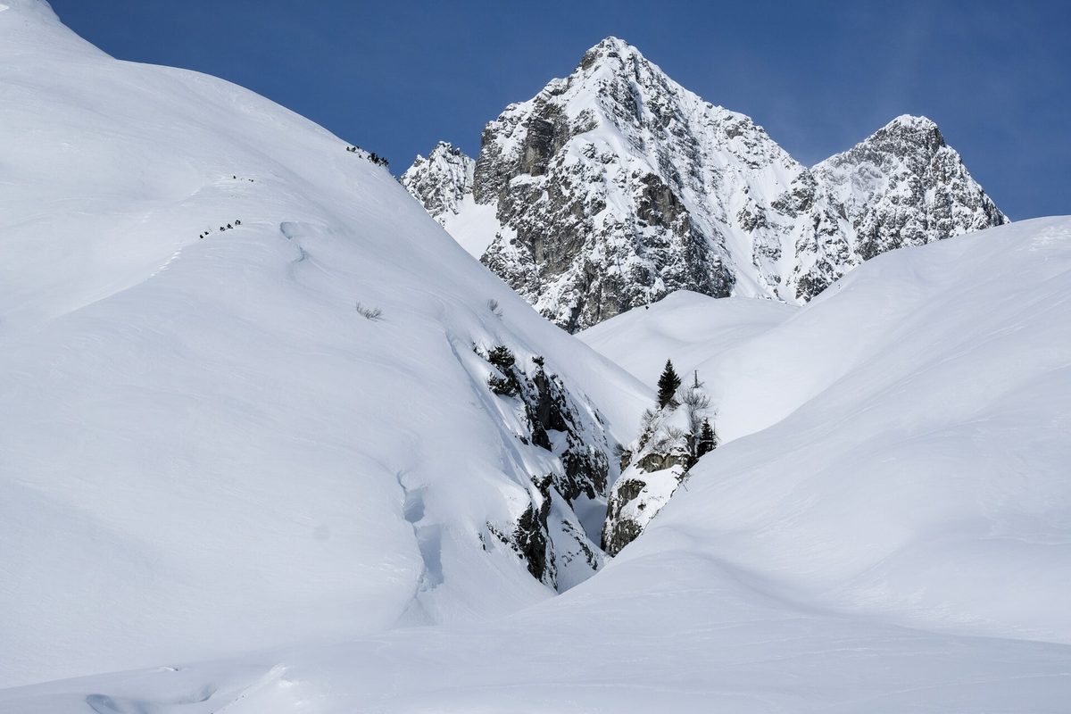 A skier carving through fresh powder snow on a sunlit Alpine piste