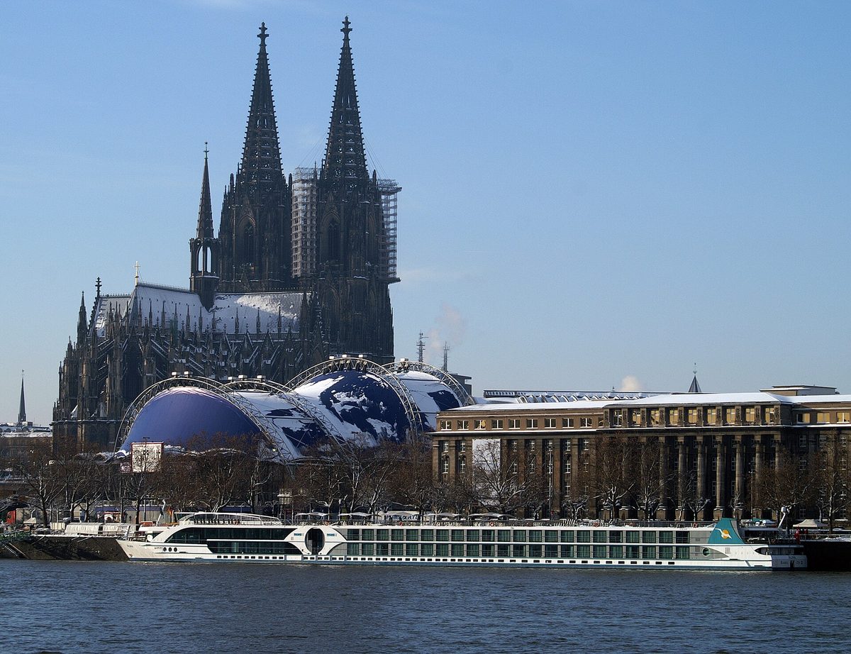 A river cruise ship on the Rhine passing Cologne's twin-spired cathedral