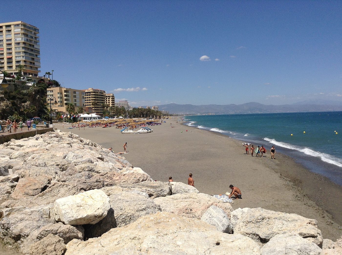 The grey sand, sunbeds and high-rise seafront of La Carihuela beach in Torremolinos