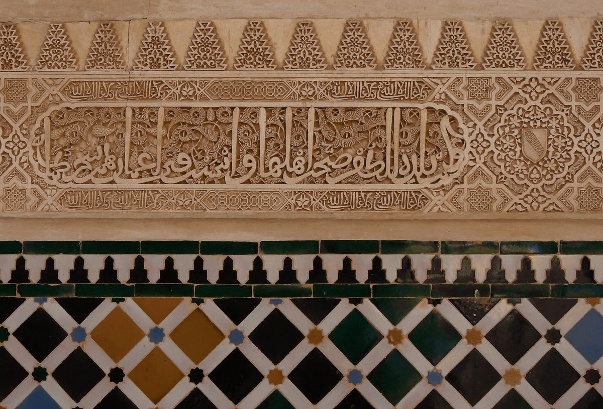 Carved stucco, Kufic inscription and glazed tilework on a wall of the Nasrid Palaces, Alhambra, Granada