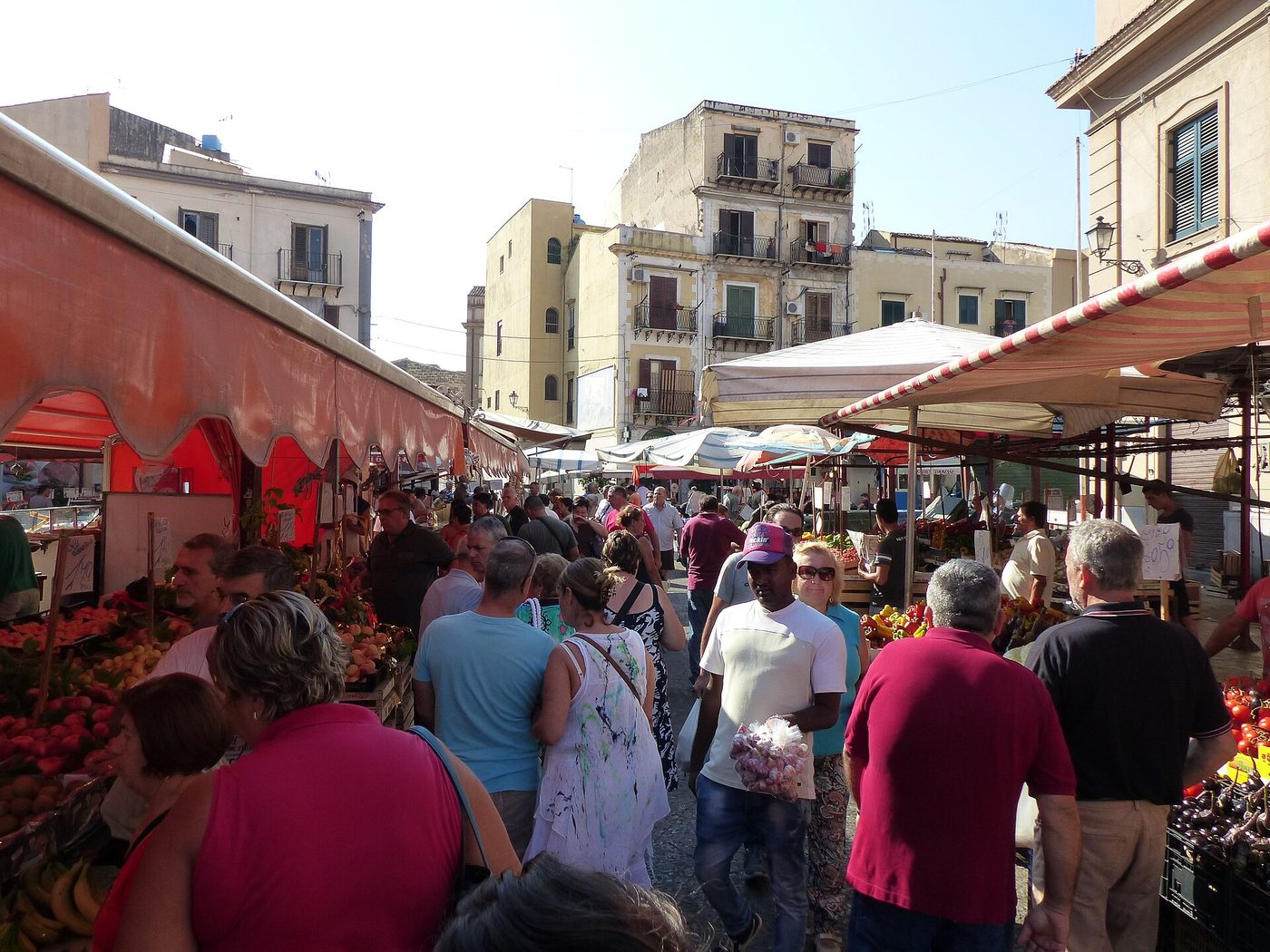 Produce stalls and shoppers at a street market in Palermo, Sicily