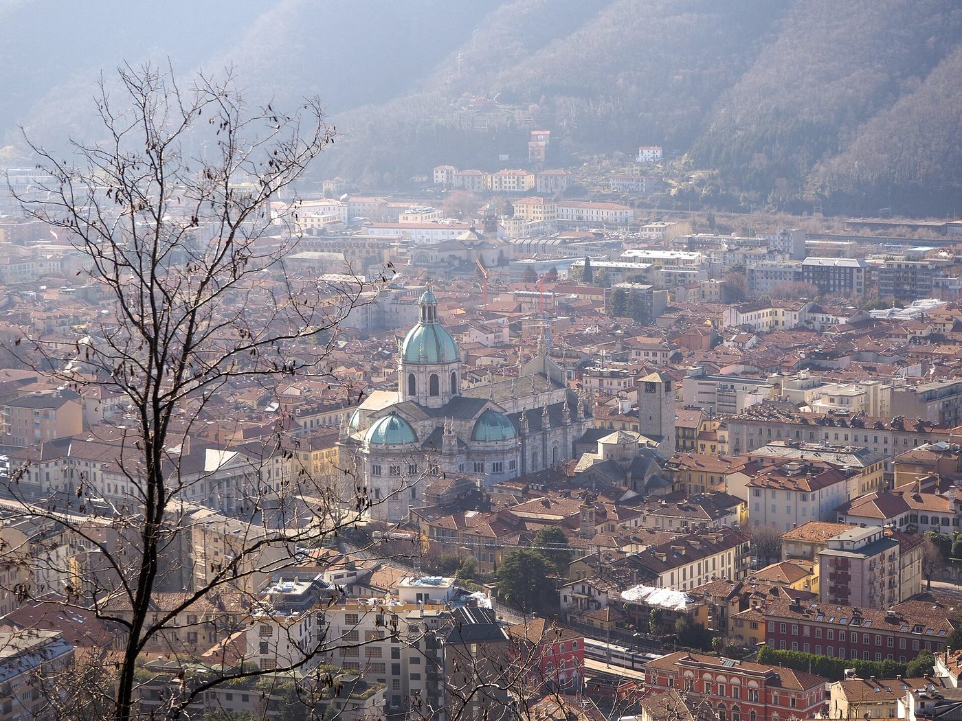 The city of Como and the green dome of its Duomo seen from the hillside above