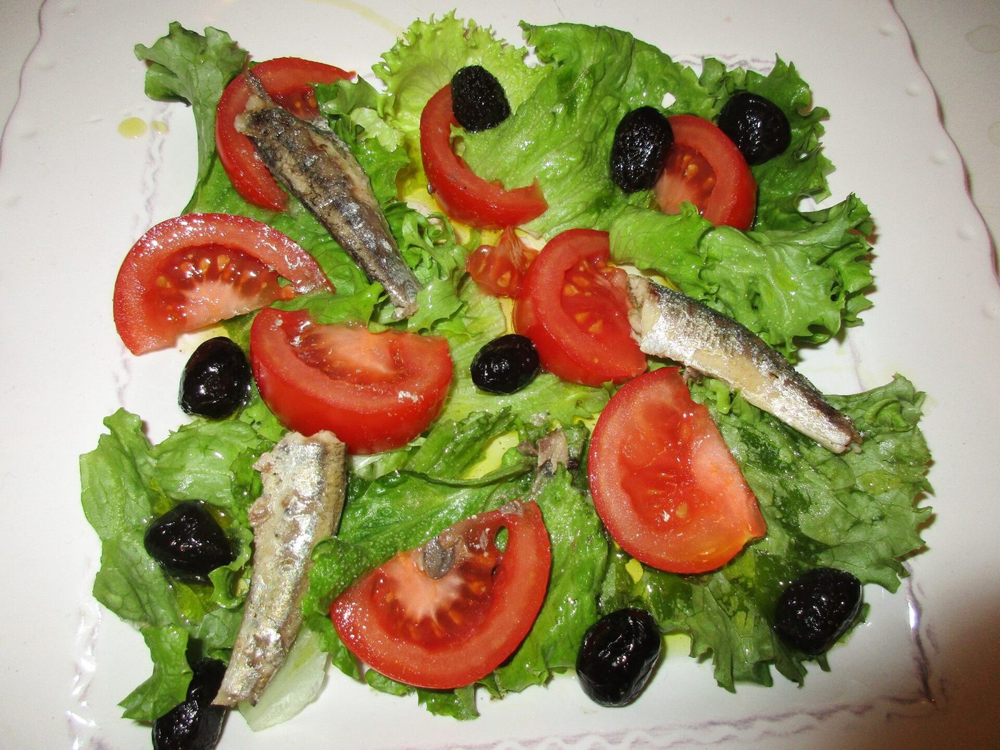 A salade nicoise of tomatoes, anchovies, olives and lettuce
