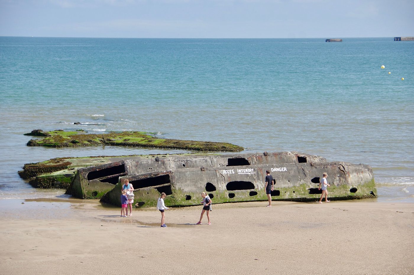 A concrete Mulberry harbour caisson beached in the shallows at Arromanches