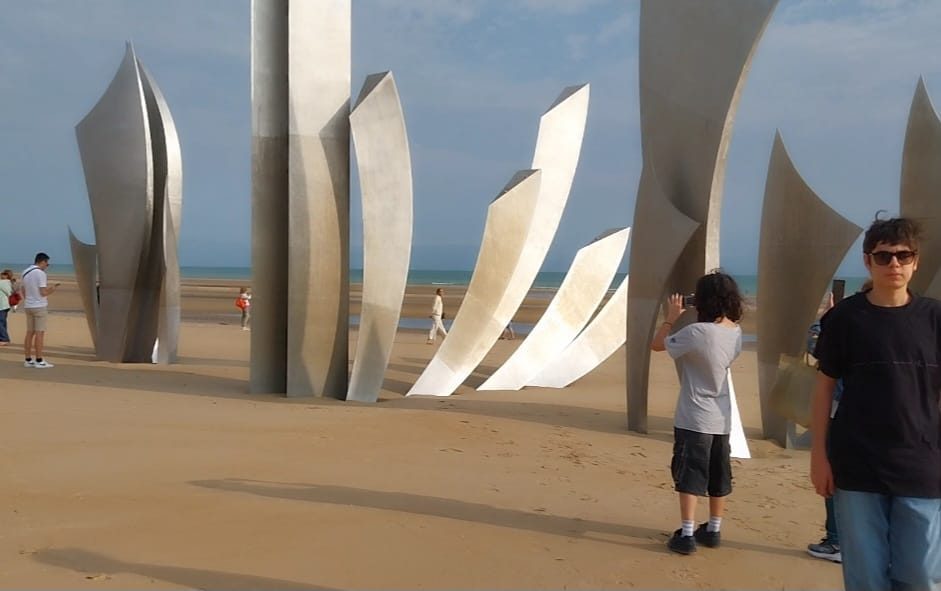 The stainless steel blades of the Les Braves memorial standing on the sand at Omaha Beach