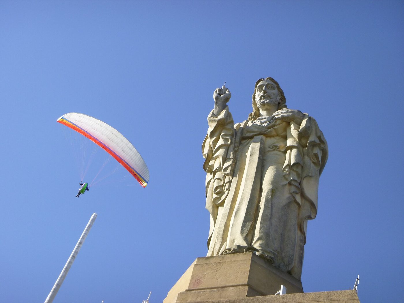 The Sagrado Corazon statue on the summit of Monte Urgull above San Sebastian, with a paraglider passing