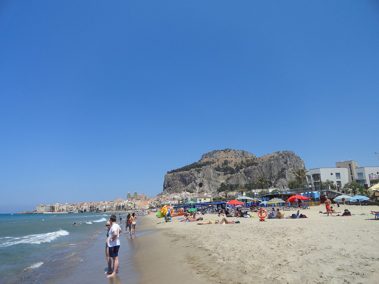 The sandy beach at Cefalu with the old town and La Rocca headland behind it
