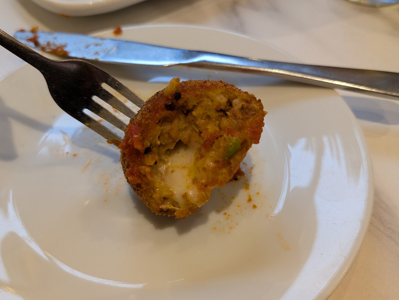 An arancino cut open to show the rice, ragu and melted cheese inside