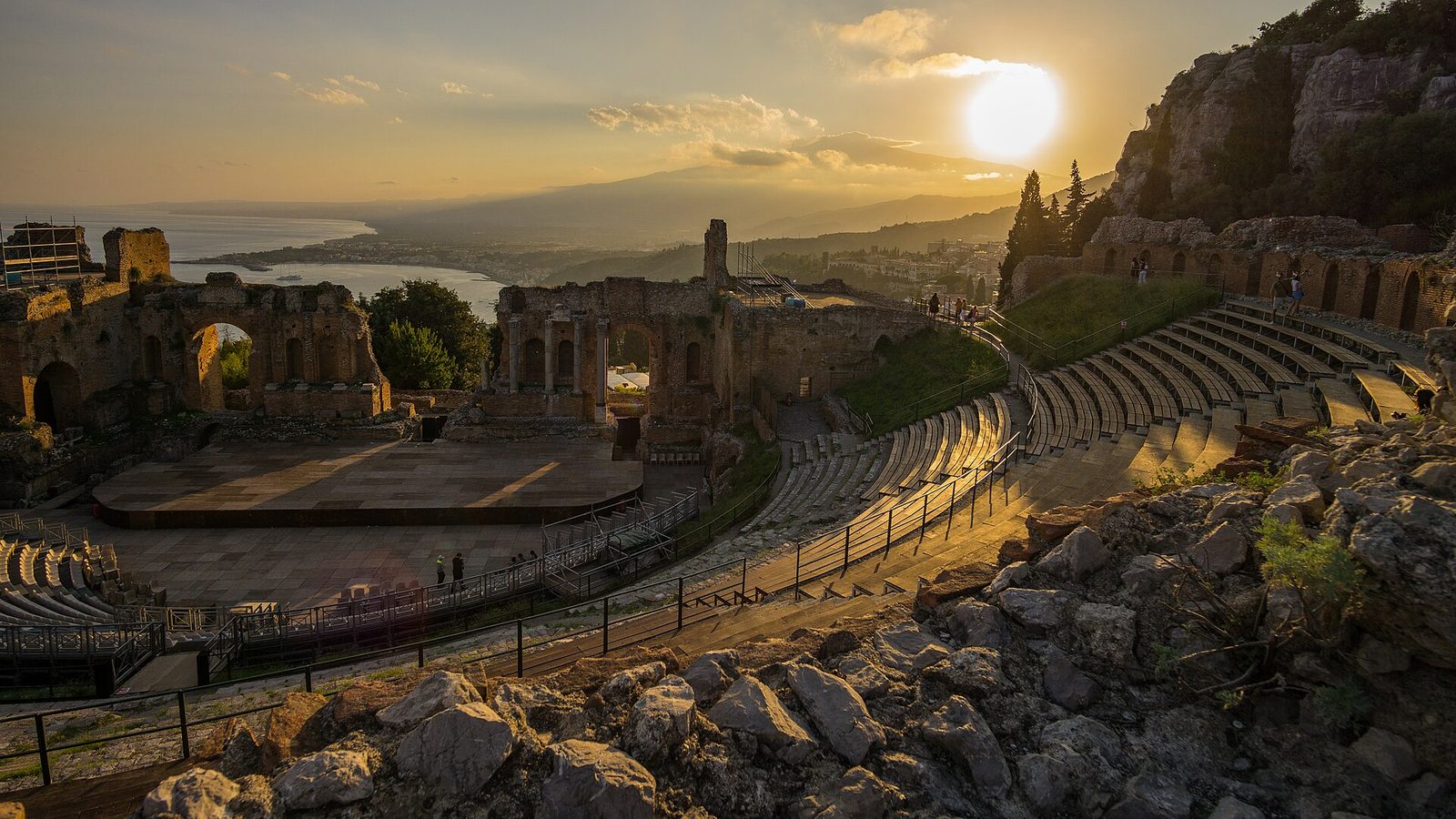 The Greek theatre at Taormina at sunset, with the bay and the bulk of Mount Etna behind it