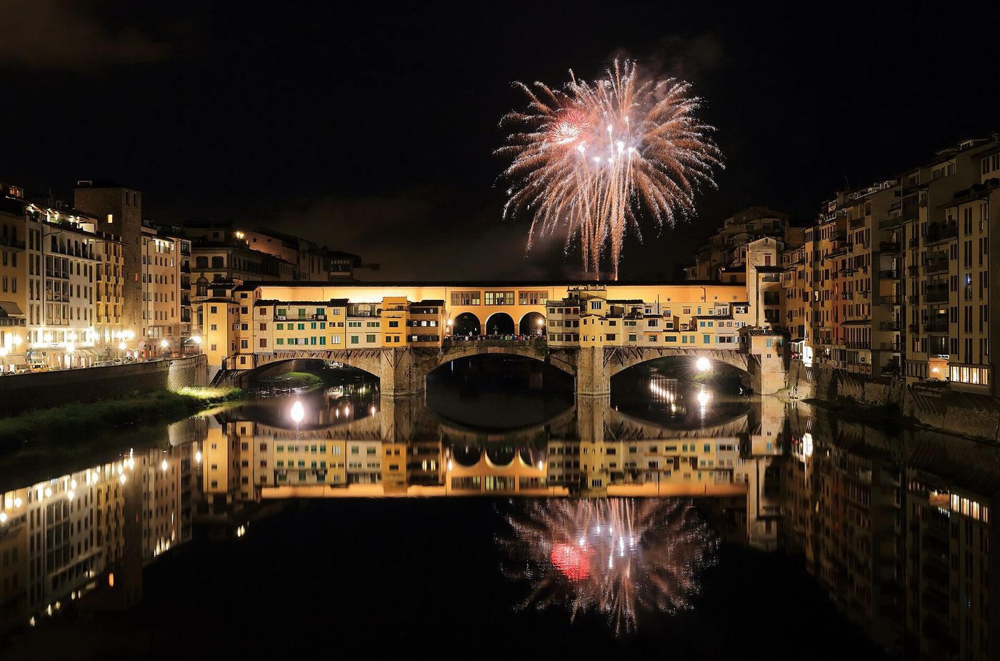 The Ponte Vecchio lit over the Arno at night with fireworks above it, Florence