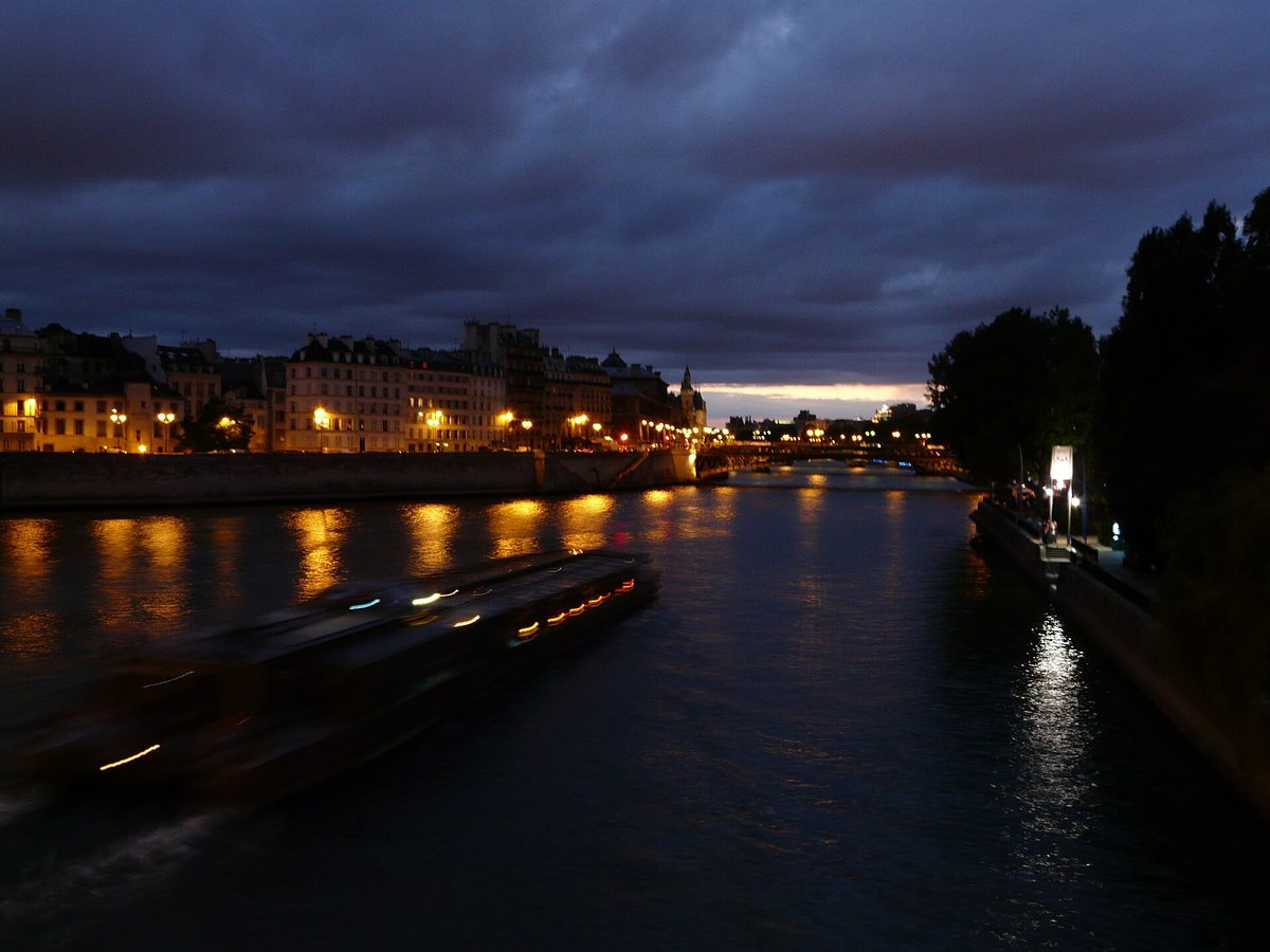 A sightseeing boat passing along the Seine in central Paris at dusk