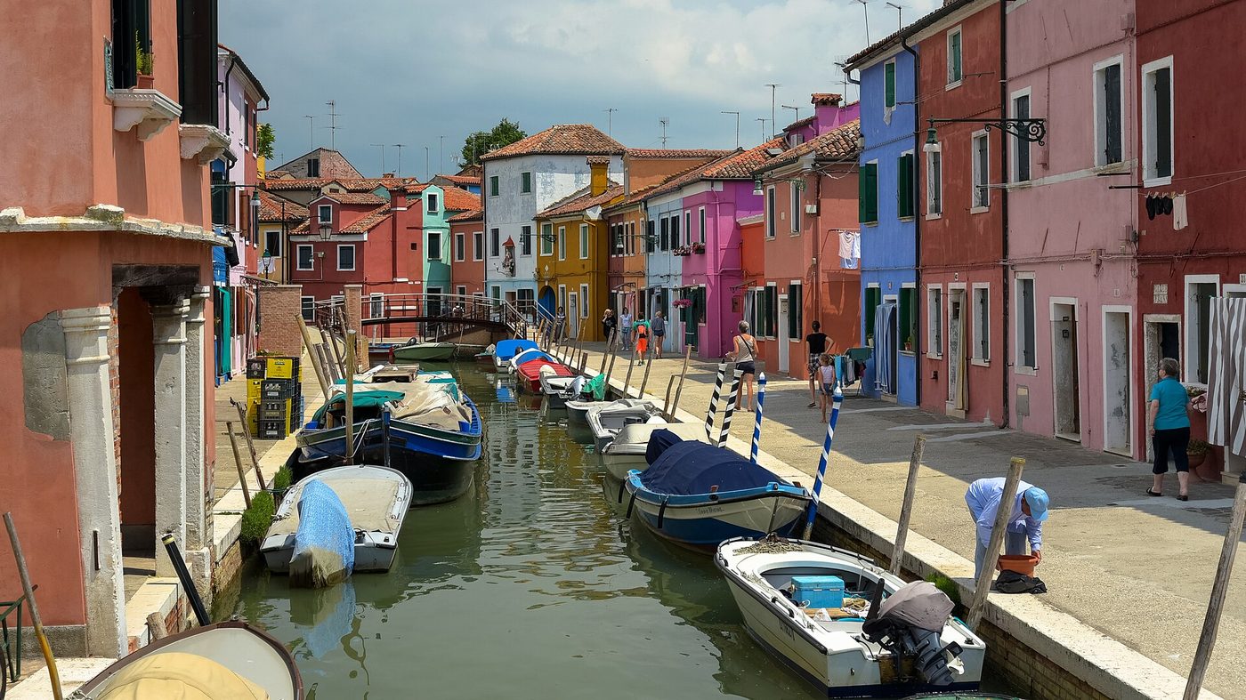 Brightly painted fishermen's houses and moored boats along a canal on Burano in the Venetian lagoon